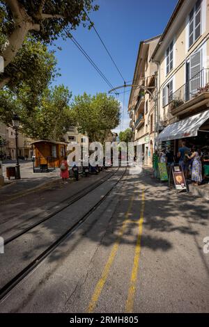 Ripresa ampia di una strada con un tram sullo sfondo e binari e linee elettriche aeree Foto Stock