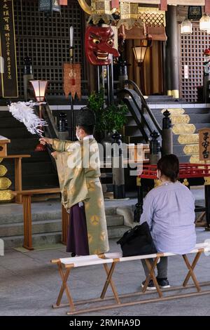 Giappone, Fukuoka, Hakata. Sacerdote shintoista che esegue una cerimonia per un adoratore al santuario shintoista Kushida. Foto Stock