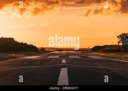 I colori oro e arancio del tramonto colpiscono la pista dell'aeroporto di Placencia, nel Belize sud-orientale Foto Stock