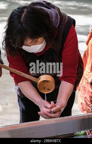 Giappone, Fukuoka, Kyushu. Santuario shintoista Sumiyoshi. Adoratore che esegue abluzioni prima di avvicinarsi al Santuario. Foto Stock