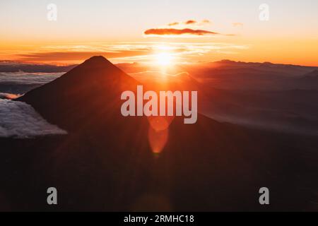 Il sole sorge da dietro il vulcano Agua in Guatemala, creando una silhouette spettacolare Foto Stock