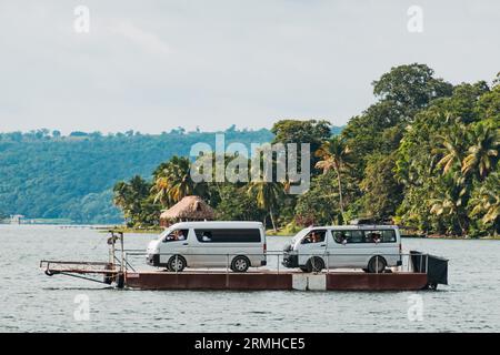 I furgoni turistici vengono trasportati su una chiatta attraverso il lago Petén Itzá fino alla città di Flores, Guatemala Foto Stock