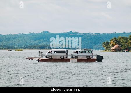 I furgoni turistici vengono trasportati su una chiatta attraverso il lago Petén Itzá fino alla città di Flores, Guatemala Foto Stock