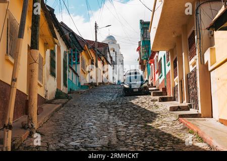 Una strada di ciottoli vuota nella città vecchia di Flores, situata su un'isola nel lago Petén Itzá, Guatemala. Cattedrale di nostra Signora di Los Remedios vista dietro. Foto Stock