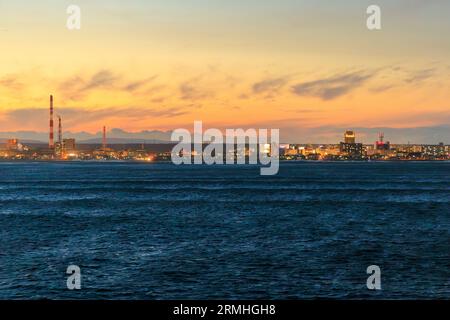 Le luci della città e i fumogeni sono visti dall'alto con il bagliore del tramonto nel cielo. Foto di alta qualità Foto Stock