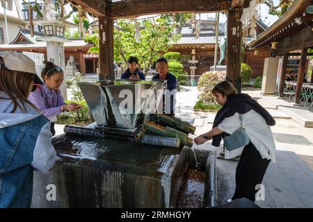 Giappone, Fukuoka. Santuario shintoista Kushida. Adoratori che eseguono abluzioni prima di avvicinarsi al Santuario. Foto Stock