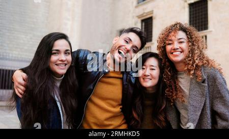 Gruppo eterogeneo di persone che si divertono insieme all'esterno - amici felici di diversa etnia che guardano la fotocamera - concentrazione sulla persona gay non binaria Foto Stock