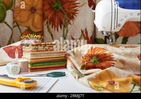 Preparazione e selezione di tessuti per cucire trapunte patchwork su una macchina da cucire elettrica Foto Stock