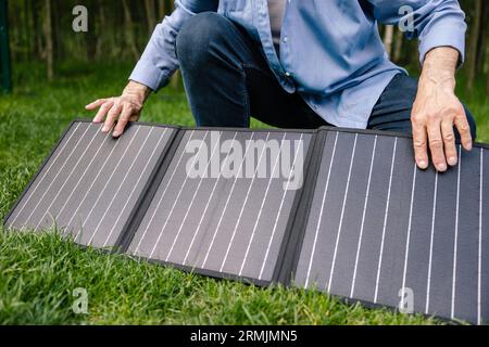 Uomo che tiene un pannello solare in giardino. Foto Stock