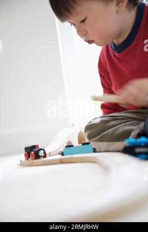 Giovane ragazzo giocando con treni di legno insieme Foto Stock