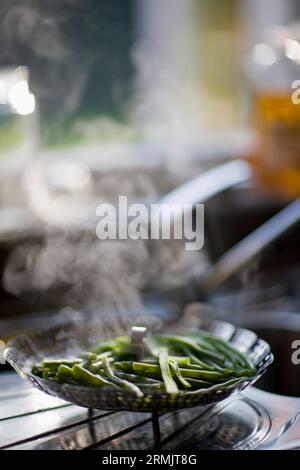 Fagioli verdi della cottura a vapore in un acciaio inossidabile sistema di cottura a vapore Foto Stock