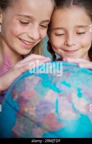 Due giovani ragazze che toccano e girano un globo mondiale Foto Stock