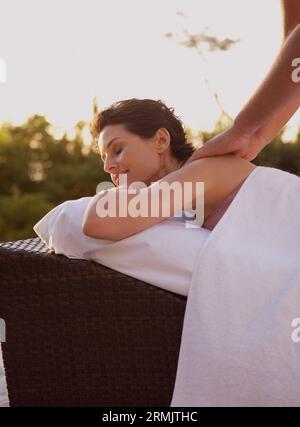 Maschio terapista di massaggio donna massaggio sulle spalle all'aperto Foto Stock