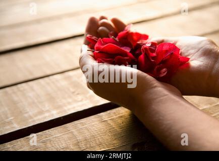 Close up della donna e delle sue mani petali di colore rosso Foto Stock