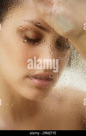 Chiudere fino a una giovane donna appoggiata contro la cottura a vapore Anta doccia Foto Stock