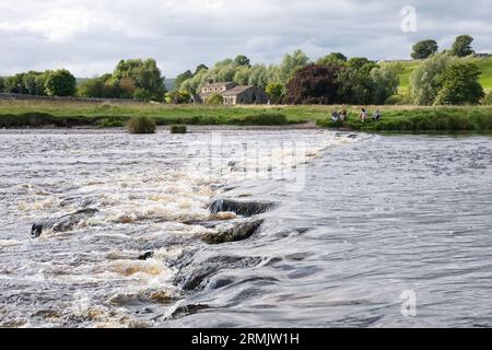 Linton Stepping Stones attraverso il River Wharfe che conduce alla chiesa di St Michael and All Angels - impraticabile dato che il fiume è alto, Linton, Skipton, Inghilterra Foto Stock