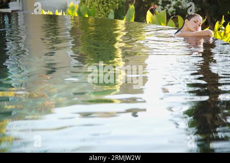 Ritratto di giovane donna in un'esotica piscina appoggiata Foto Stock