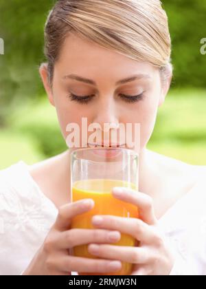 Chiudere fino a una giovane donna con in mano un bicchiere di succo di arancia Foto Stock
