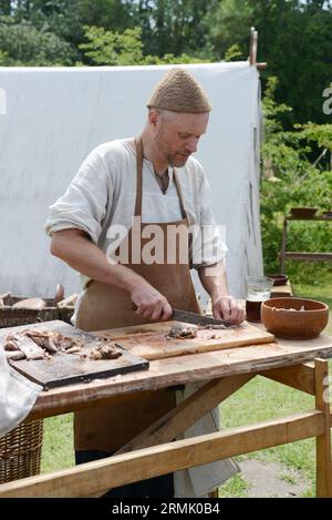 Un uomo danese che taglia carne arrosto al Trelleborgs Viking Festival di Slagelse, in Zelanda, Danimarca. Foto Stock