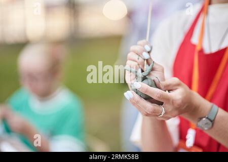 Un maestro ceramista tiene in mano un prodotto di argilla. Fare un animale di ceramica dall'argilla. Il processo di modellazione con strumenti per creare un capolavoro. Foto di alta qualità Foto Stock