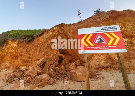SCOGLIERE INSTABILI A CADUTA ROCCIOSA, MANTENERE Una DISTANZA DI SICUREZZA è scritto in inglese su un cartello di avvertimento in Portogallo sulle scogliere dell'Oceano Atlantico. Rocce e. Foto Stock