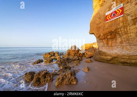 SCOGLIERE INSTABILI A CADUTA ROCCIOSA, MANTENERE Una DISTANZA DI SICUREZZA è scritto in inglese su un cartello di avvertimento in Portogallo sulle scogliere dell'Oceano Atlantico. Rocce e. Foto Stock