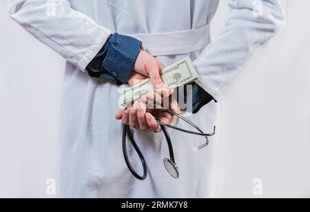 Un medico disonesto che nasconde soldi. Corruzione medica e concetto di corruzione, medico corrotto che nasconde denaro indietro Foto Stock