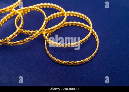 Bracciale twist in oro turco da 24 carati in un mucchio su uno sfondo blu scuro nel negozio d'oro Foto Stock