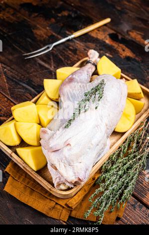 Faraona cruda fresca, faraona con patate, selvaggina. Sfondo di legno. Vista dall'alto. Foto Stock