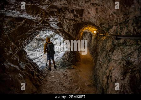 Arrampicatori lungo il percorso attraverso l'Hoellentalklamm, in un passaggio di grotta, stretta gola di roccia con ruscello di montagna, montagne Wetterstein Foto Stock