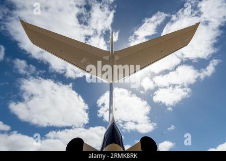 Coda di un aereo privato a reazione, blu e bianco contro un cielo blu nuvoloso - orizzontale Foto Stock