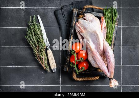 Selvaggina uccello guineafowl crudo, faraona pronto per la cottura. Sfondo nero. Vista dall'alto. Foto Stock