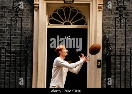 Jake Barraclough lancia una palla di rugby fuori dal 10 di Downing Street, Londra, mentre segna il 200° anniversario della creazione del gioco di rugby correndo i 450 km dalla Rugby School a Parigi, prima della Coppa del mondo di rugby in Francia. Data foto: Martedì 29 agosto 2023. Foto Stock