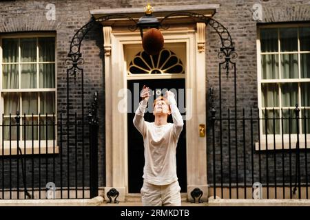 Jake Barraclough lancia una palla di rugby fuori dal 10 di Downing Street, Londra, mentre segna il 200° anniversario della creazione del gioco di rugby correndo i 450 km dalla Rugby School a Parigi, prima della Coppa del mondo di rugby in Francia. Data foto: Martedì 29 agosto 2023. Foto Stock