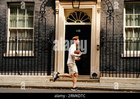Jake Barraclough corre con una palla di rugby fuori dal 10 di Downing Street, Londra, in occasione del 200° anniversario della creazione del gioco di rugby correndo i 450 km dalla Rugby School a Parigi, prima della Coppa del mondo di rugby in Francia. Data foto: Martedì 29 agosto 2023. Foto Stock
