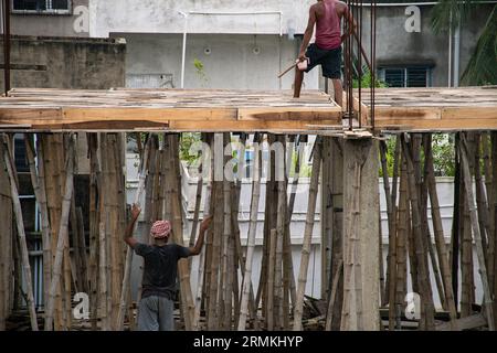 I massoni stanno lavorando con bamboo e pannelli di legno in un alto edificio in costruzione Foto Stock