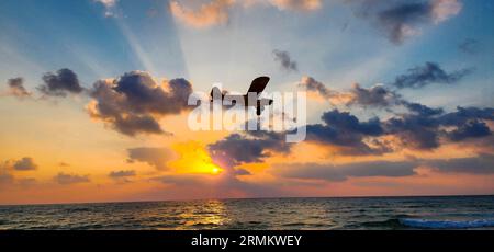 Un aereo giallo con elica leggera sta attraversando il cielo durante il tramonto Foto Stock