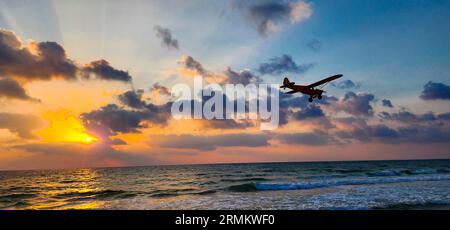 Un aereo giallo con elica leggera sta attraversando il cielo durante il tramonto Foto Stock