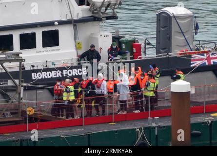 Un gruppo di persone che si pensa siano migranti arriva a dover, nel Kent, a bordo della nave Defender della Border Force dopo aver attraversato la Manica in una piccola barca che viaggia dalla costa della Francia. Data foto: Martedì 29 agosto 2023. Foto Stock