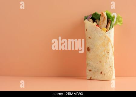 Delizioso involtino di pollo con lattuga fresca e pomodori maturi in tortilla su sfondo chiaro. Copia spazio per testo Foto Stock