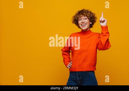 Gioiosa zenzero di mezza età che ha un'idea e punta il dito verso l'alto isolato su sfondo giallo Foto Stock