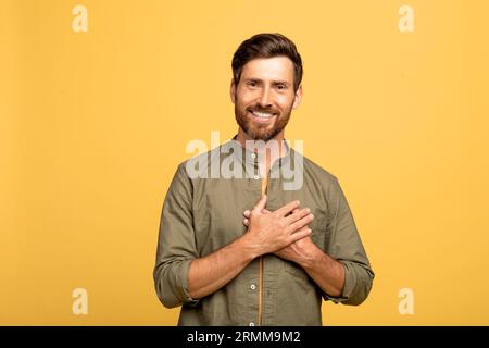 Concetto di gratitudine. Uomo grato allegro di mezza età che tiene le mani sul petto e sorride, esprimendo apprezzamento Foto Stock