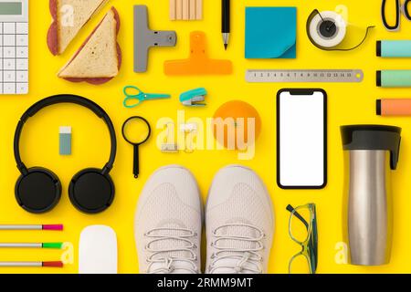 Cancelleria, forniture scolastiche a terra. con mockup di telefono mboile. L'appartamento di ritorno a scuola si trovava su sfondo giallo Foto Stock