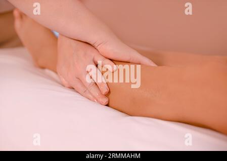 Trattamento dell'osteopatia sulla gamba del paziente. closeup massaggiatrice mani fare massaggio gambe per cliente donna Foto Stock