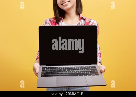Donna cinese che tiene in mano un notebook con schermo nero vuoto, dimostrando il nuovo design del sito Web, il mockup e il primo piano Foto Stock