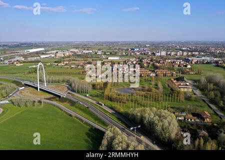 Veduta aerea zenithal di una rotatoria con un arco del ponte sospeso di Santiago Calatrava a Reggio Emilia. Reggio Emilia, Italia Foto Stock