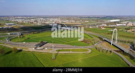 Veduta aerea zenithal di una rotatoria con un arco del ponte sospeso di Santiago Calatrava a Reggio Emilia. Reggio Emilia, Italia Foto Stock