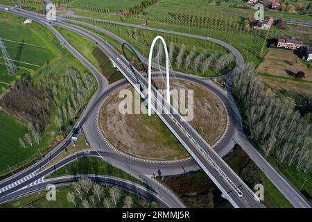 Veduta aerea zenithal di una rotatoria con un arco del ponte sospeso di Santiago Calatrava a Reggio Emilia. Reggio Emilia, Italia Foto Stock