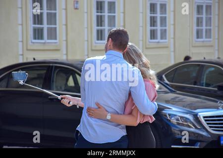 Turisti felici a Praga, Repubblica Ceca, che scattano selfie e foto di un altro passeggero in una giornata di sole durante le loro vacanze. Foto Stock