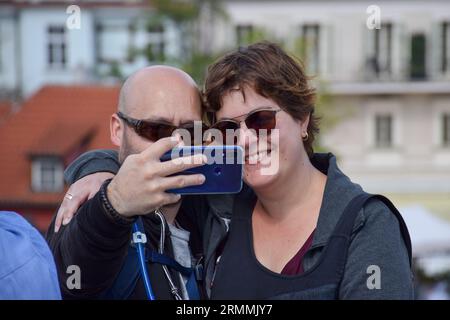 Turisti felici a Praga, Repubblica Ceca, che scattano selfie e foto di un altro passeggero in una giornata di sole durante le loro vacanze. Foto Stock